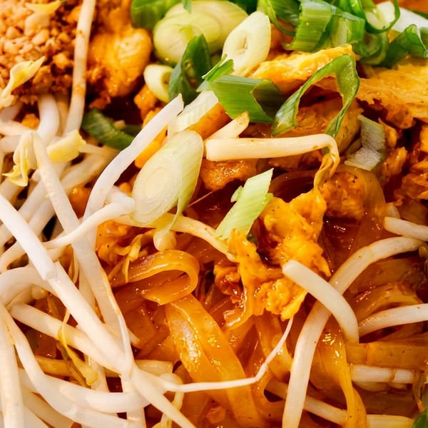 Vibrant Pad Thai dish with noodles, bean sprouts, crushed peanuts, green onions, and egg.